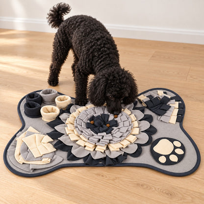 Black poodle sniffing the centre of the grey bone-shaped snuffle mat with treats on it