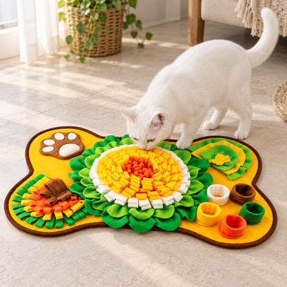 White cat sniffing the centre of the yellow and green bone-shaped snuffle mat