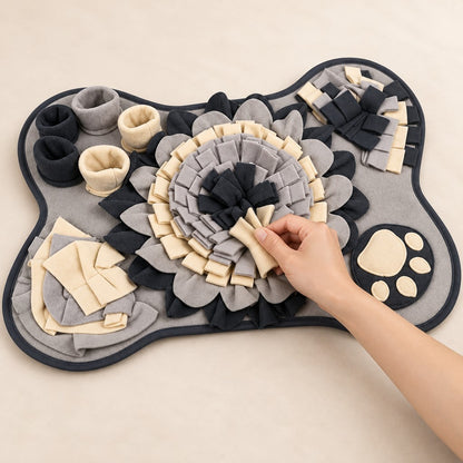 Hand lifting a cream fabric strip in the centre rosette of the grey bone-shaped mat