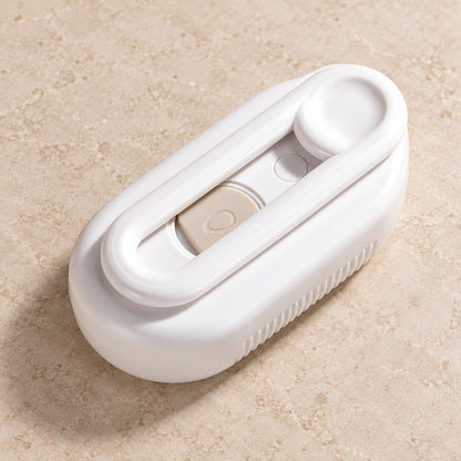 Back of the white brush with its looped handle folded flat, resting on a marble-look surface