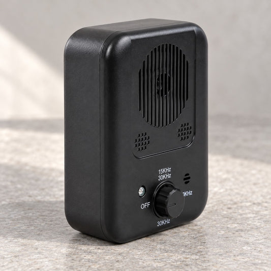 Black ultrasonic dog training device in three-quarter view showing front grille and dial