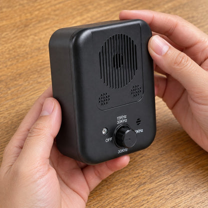 Two hands holding the black device, with the rotary dial and printed settings facing the camera