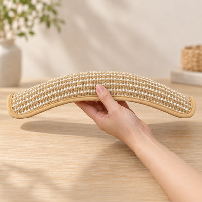 Hand bending the soft striped pillow into an arc, held above a wooden table