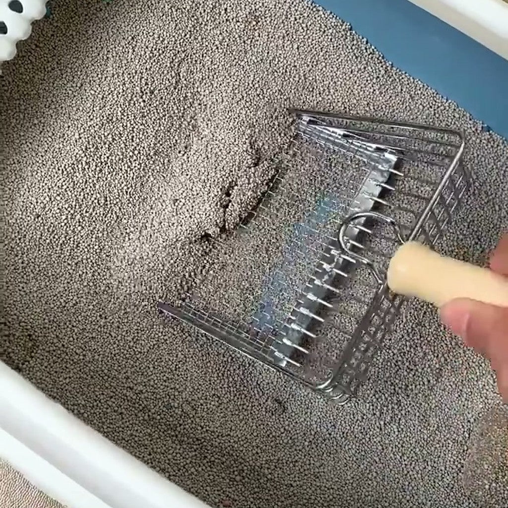 Hand pressing the mesh litter scoop into grey litter in a white tray
