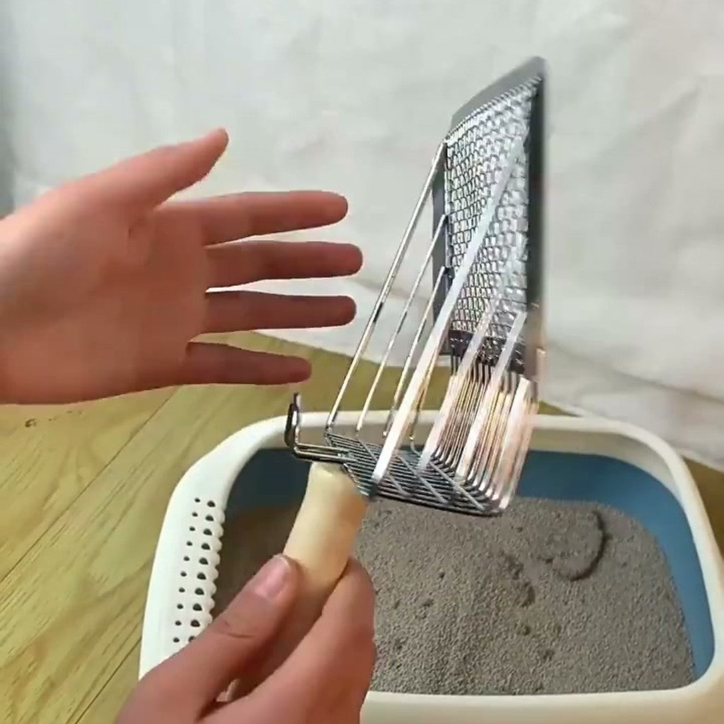 Hand holding the scoop over a litter tray, showing its mesh floor and open rods