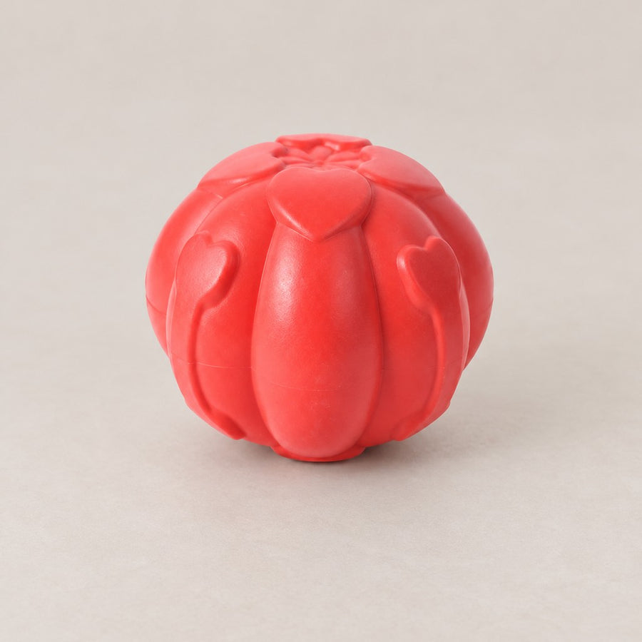 Red moulded dog ball with raised heart-shaped ribs and a petal pattern on top