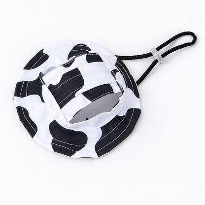 Black and white cow-print bucket hat with ear opening and black chin cord on white background